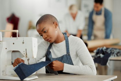 Fashion, design and creative work at a workshop. Young african American factory worker sewing new,