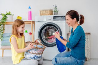 Happy mother and little daughter washing clothes