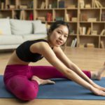 Improve flexibility. Young japanese lady stretching leg and hamstring muscles on yoga mat before