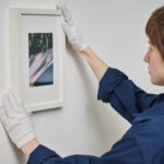 Woman hanging framed photo on the wall