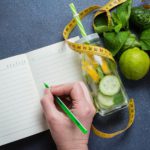 Woman writing nutrition plan diet menu and fitness workout routine.
